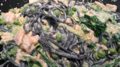 Черные спагетти с красной рыбой, зелёным горошком и голубым сыром
