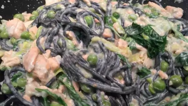 черные спагетти с красной рыбой зелёным горошком и голубым сыром